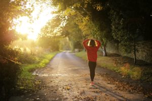 Woman walking on park trail as the sun rises.